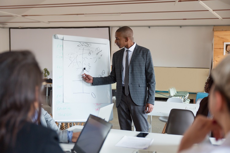 confident speaker talking and pointing at whiteboard